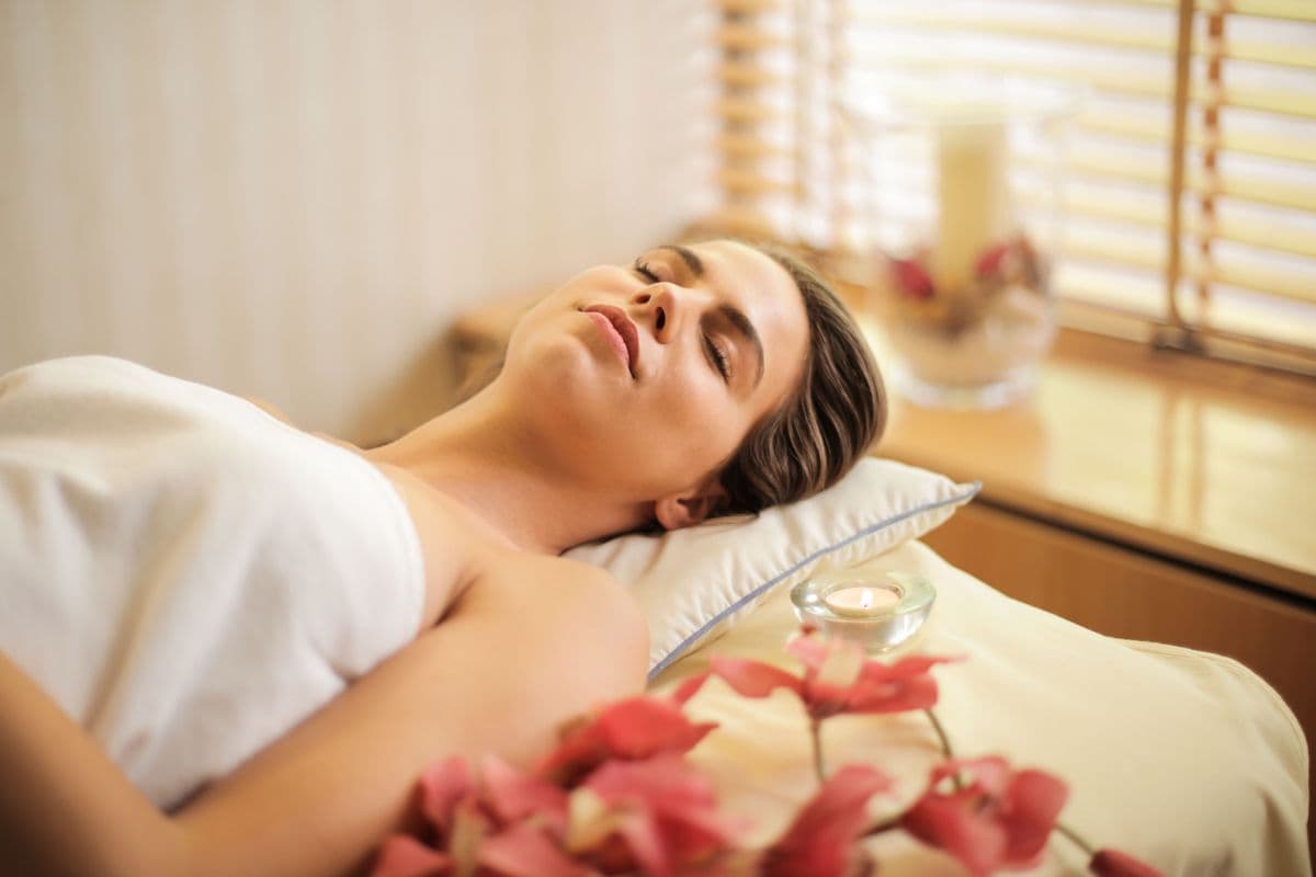 Person relaxing and recovering in a calm, candlelit spa setting