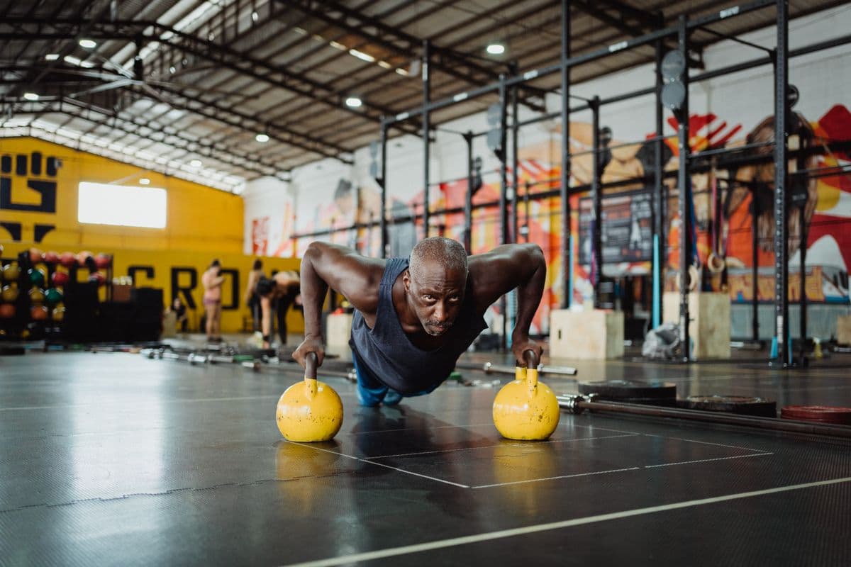 Mature athlete doing push-ups on kettlebells in a functional-fitness gym